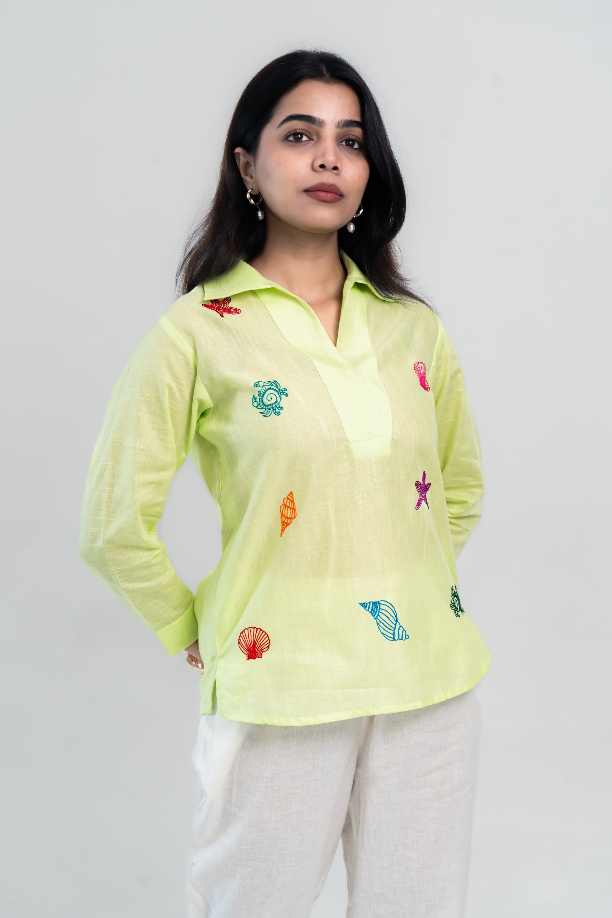 Lime green embroidered shirt with colorful sea motifs, paired with white pants for casual wear