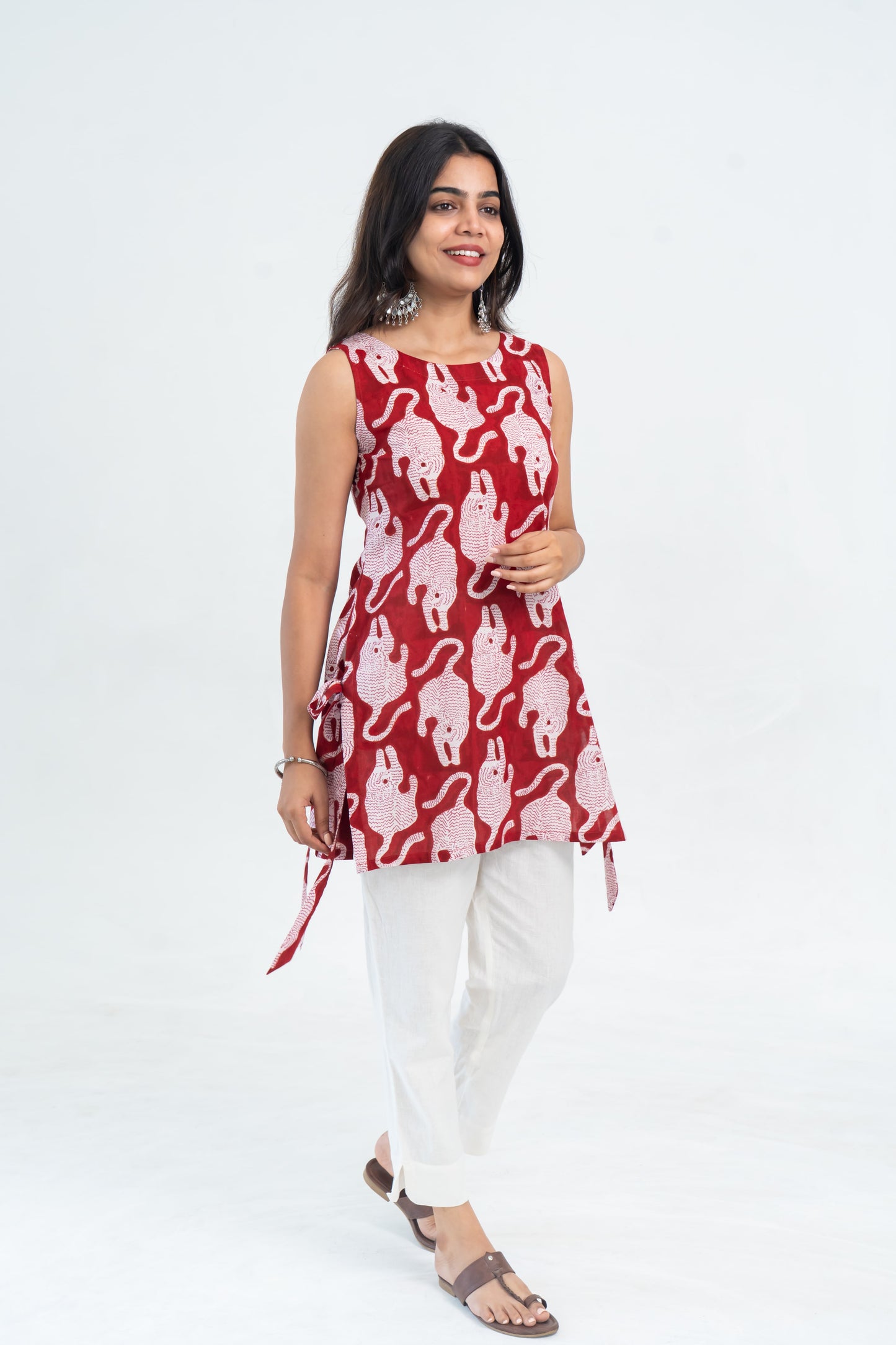 Red sleeveless top with white animal print paired with white pants and sandals