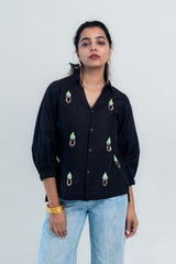 Black embroidered shirt with colorful floral details, paired with light blue jeans