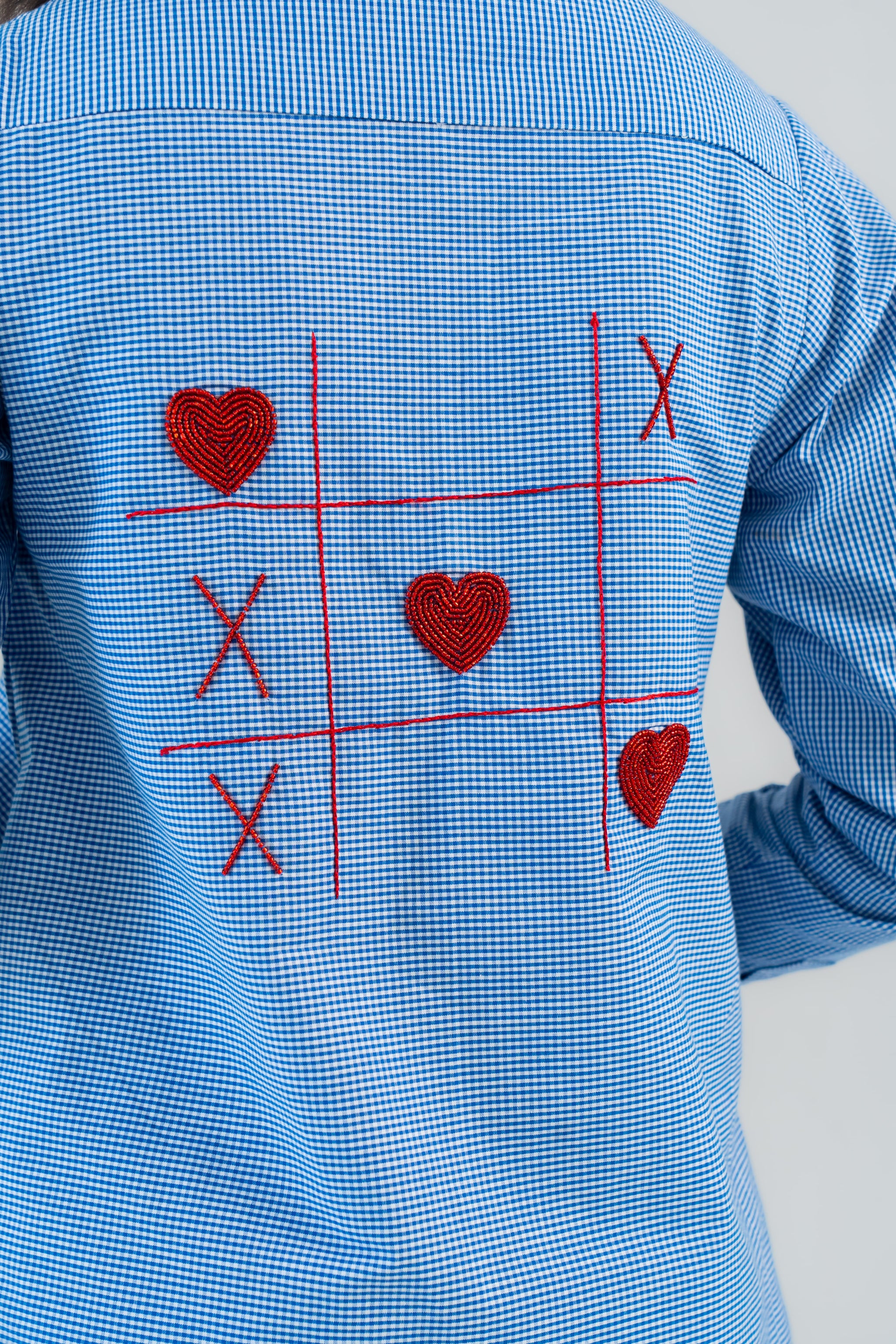 Blue gingham shirt with red heart and X embroidery in tic-tac-toe design
