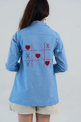 Blue gingham shirt with red heart and X embroidery back view, women's trendy top