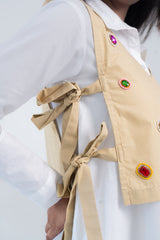Beige vest with colorful gem embellishments and tie-back detail over white shirt