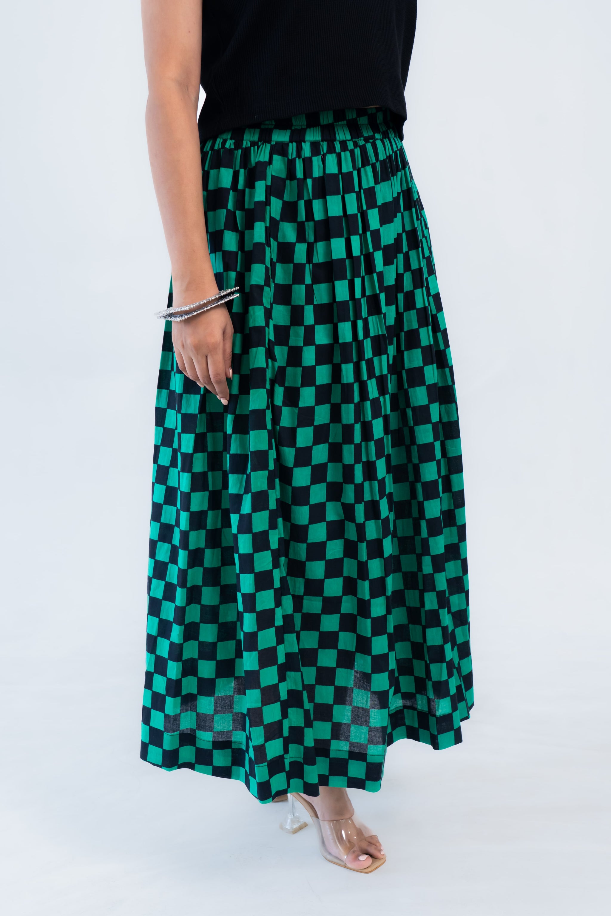 Green and black checkered maxi skirt with elastic waist, paired with black top and clear heels
