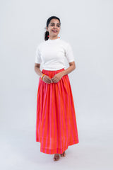 Woman in white ribbed top and vibrant orange-pink striped pleated midi skirt, stylish everyday outfit