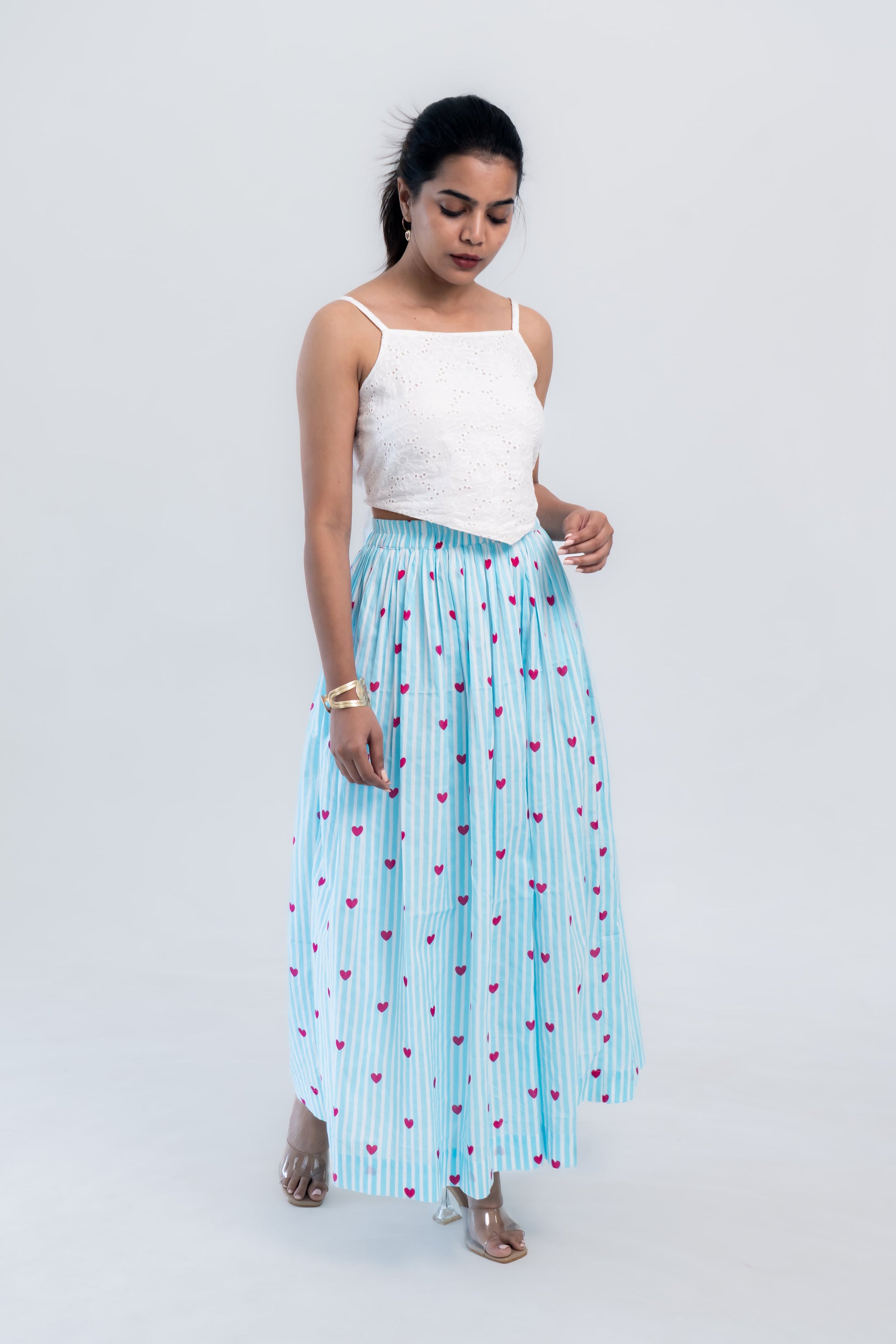 Woman in white crop top and blue striped skirt with pink hearts, stylish everyday outfit