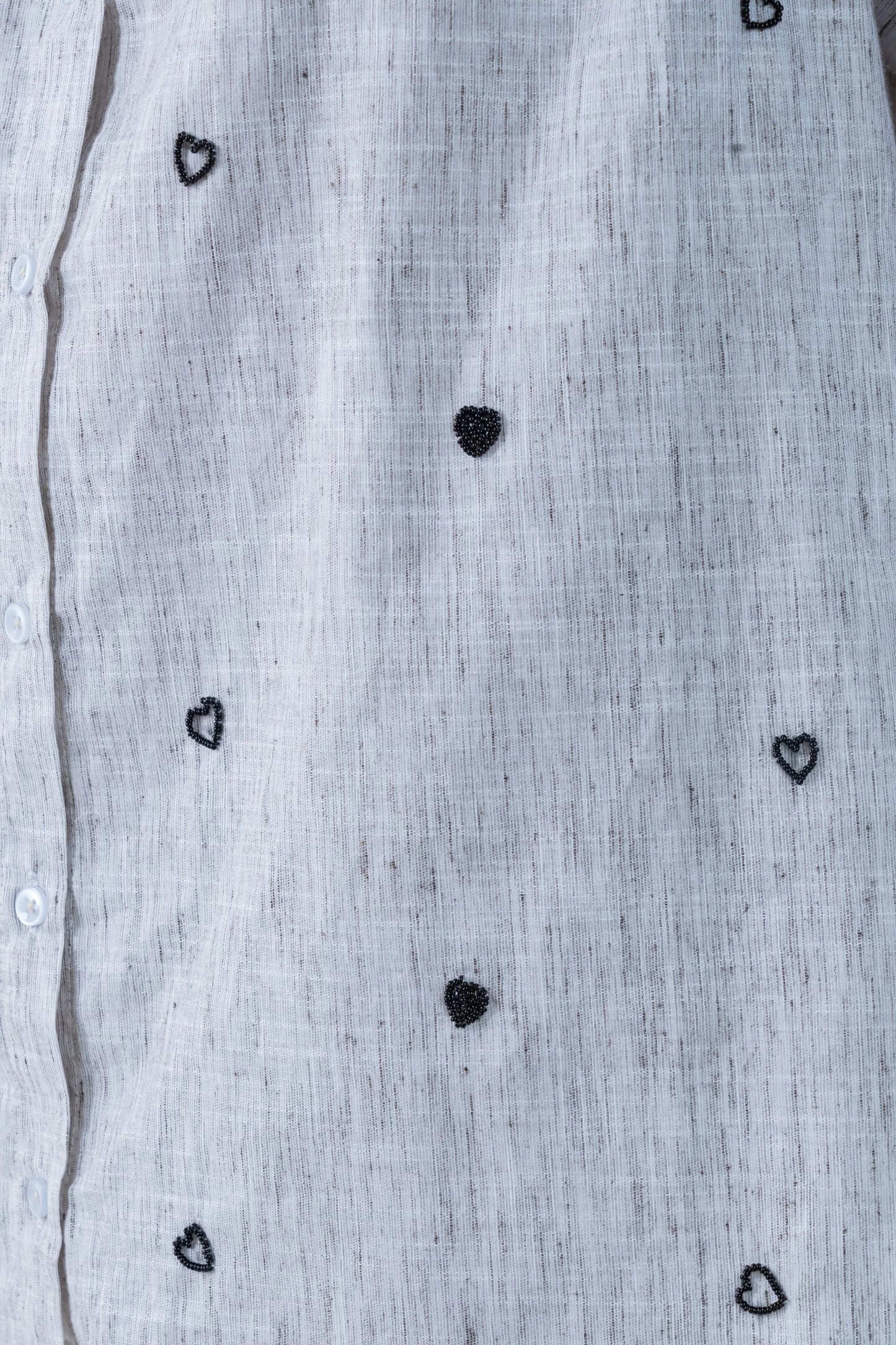 Light gray linen shirt with black beaded heart patterns and white buttons