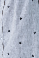 Light gray linen shirt with black beaded heart patterns and white buttons