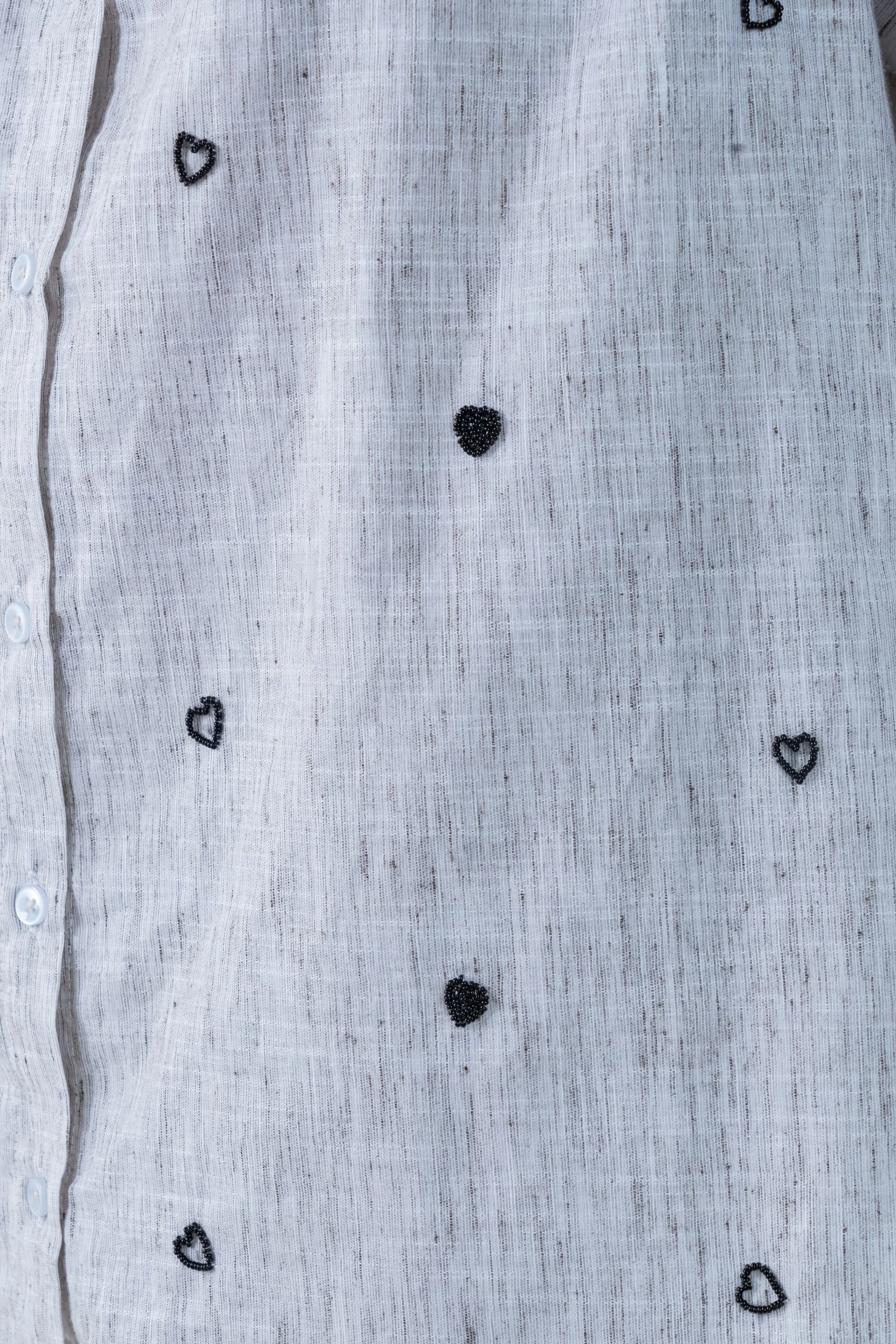 Light gray linen shirt with black beaded heart patterns and white buttons