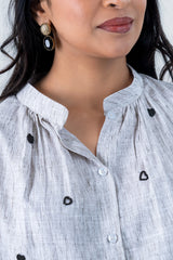 Stylish white shirt with black heart embroidery and gold earrings