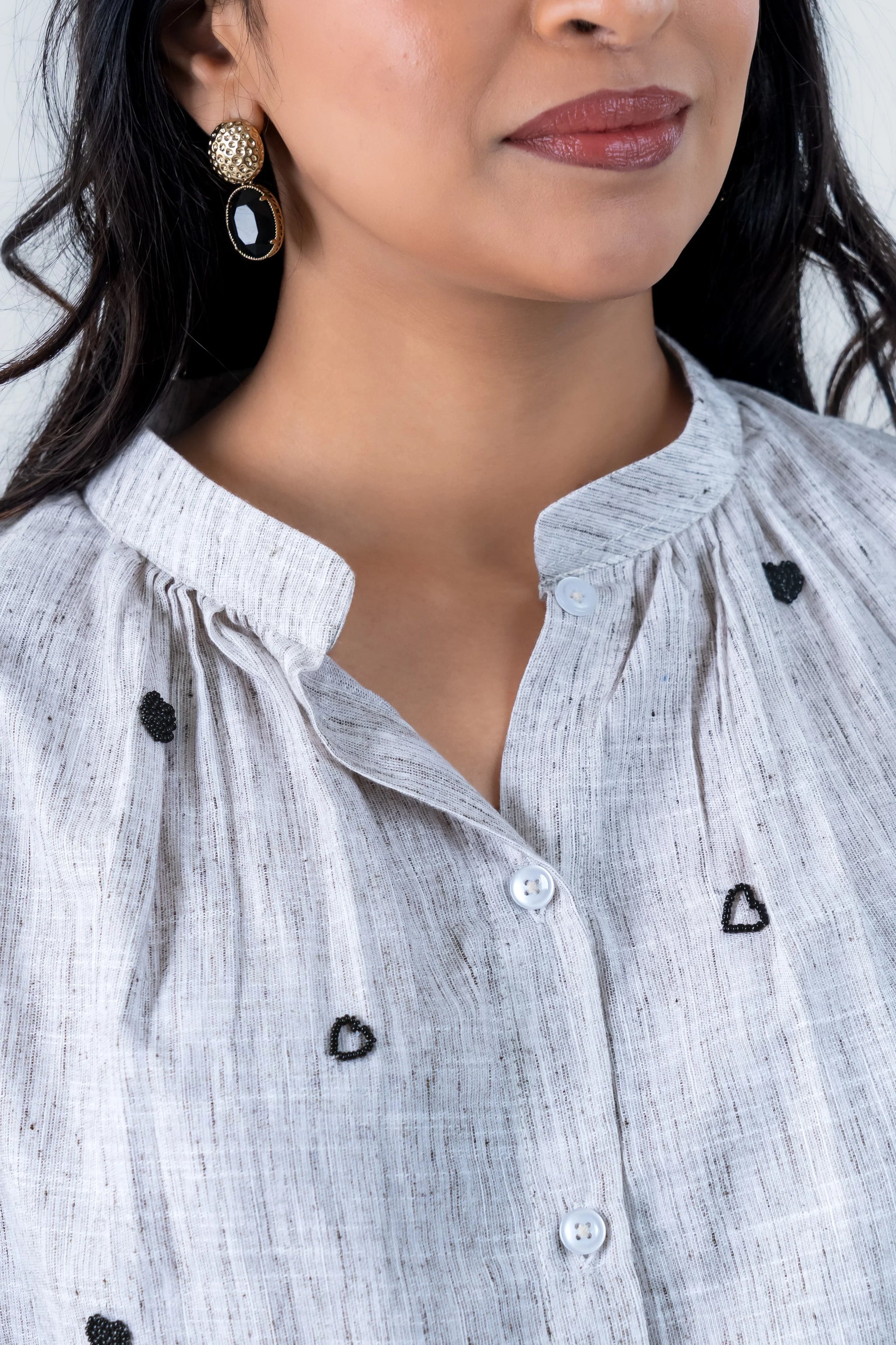 Stylish white shirt with black heart embroidery and gold earrings
