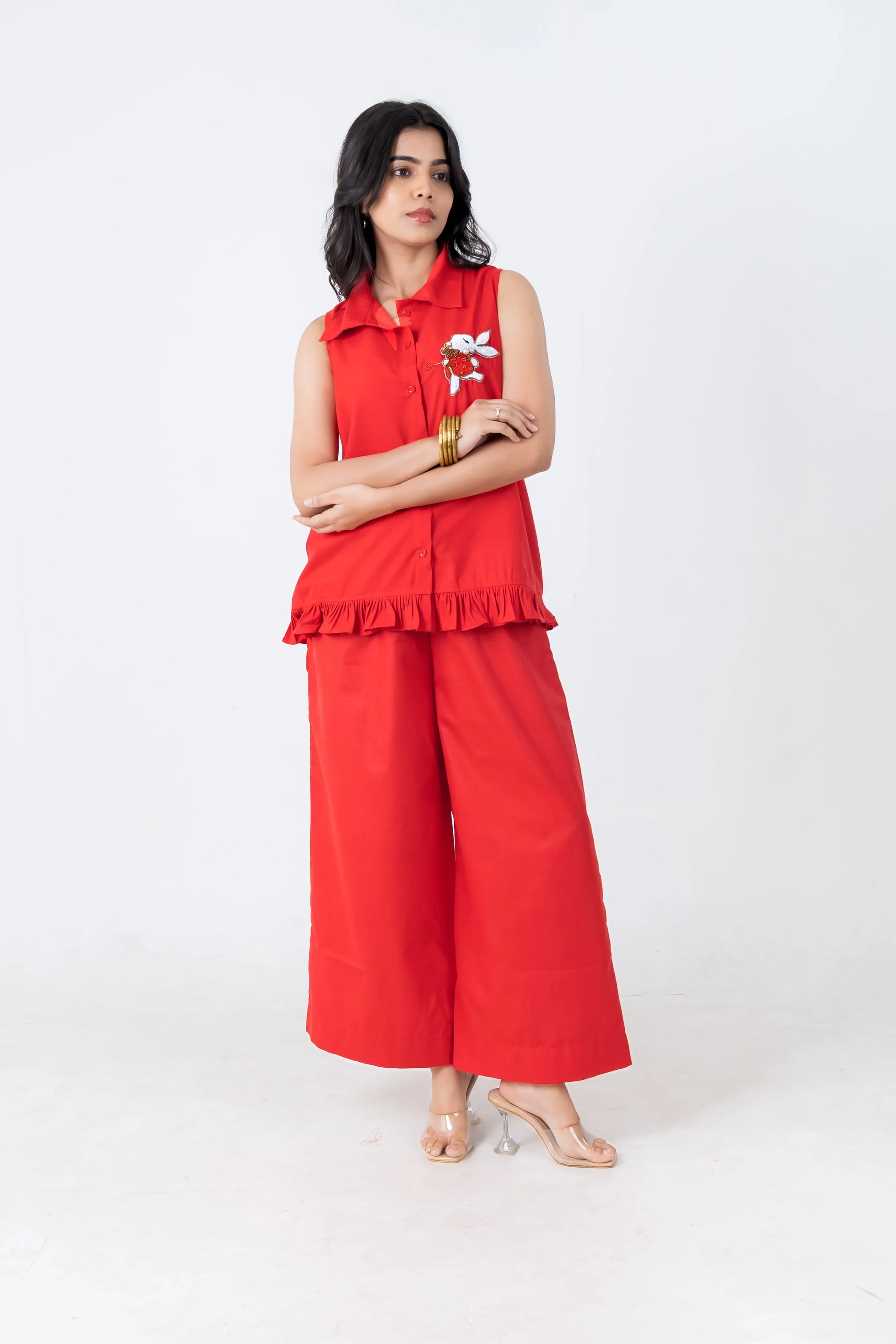 Red sleeveless co-ord set with floral embroidery and ruffle hem, paired with wide-leg pants and heels