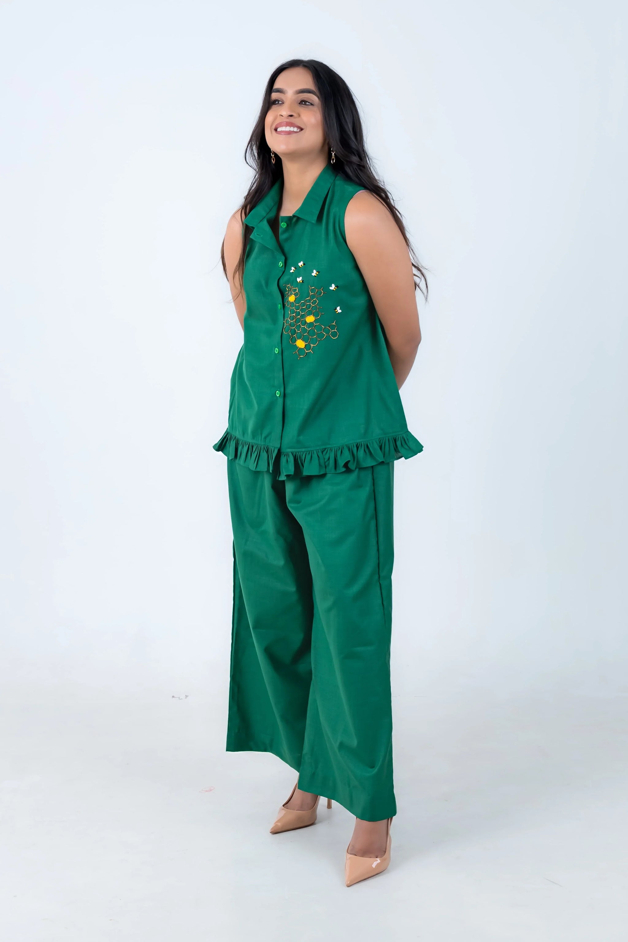 Green sleeveless co-ord set with bee embroidery and ruffle hem, paired with beige heels