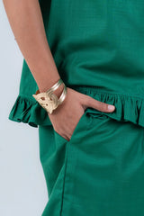 Emerald green ruffled dress with gold woven cuff bracelet