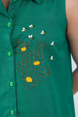 Green sleeveless dress with bee and honeycomb embroidery, featuring vibrant green buttons.