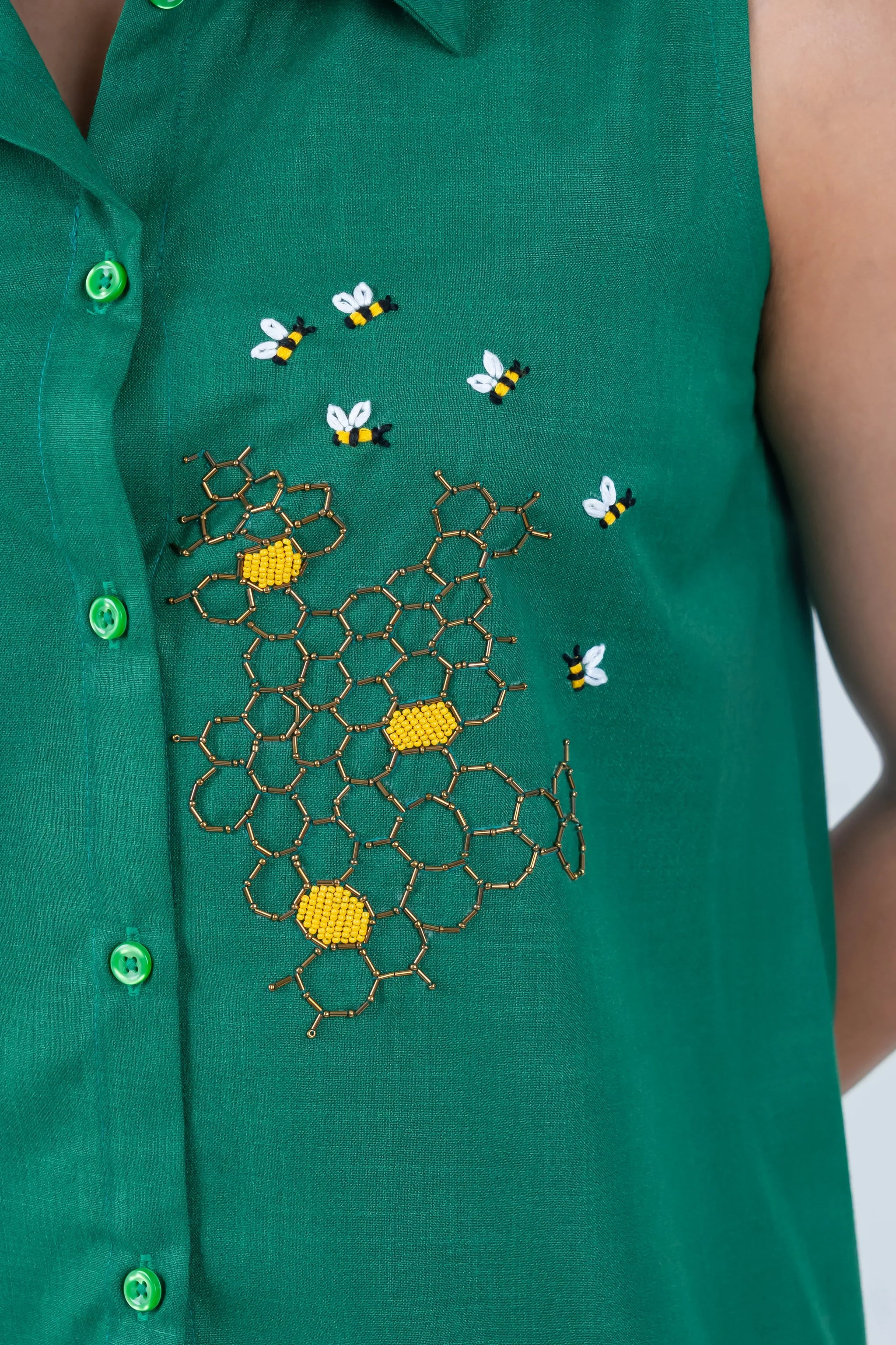 Green sleeveless dress with bee and honeycomb embroidery, featuring vibrant green buttons.