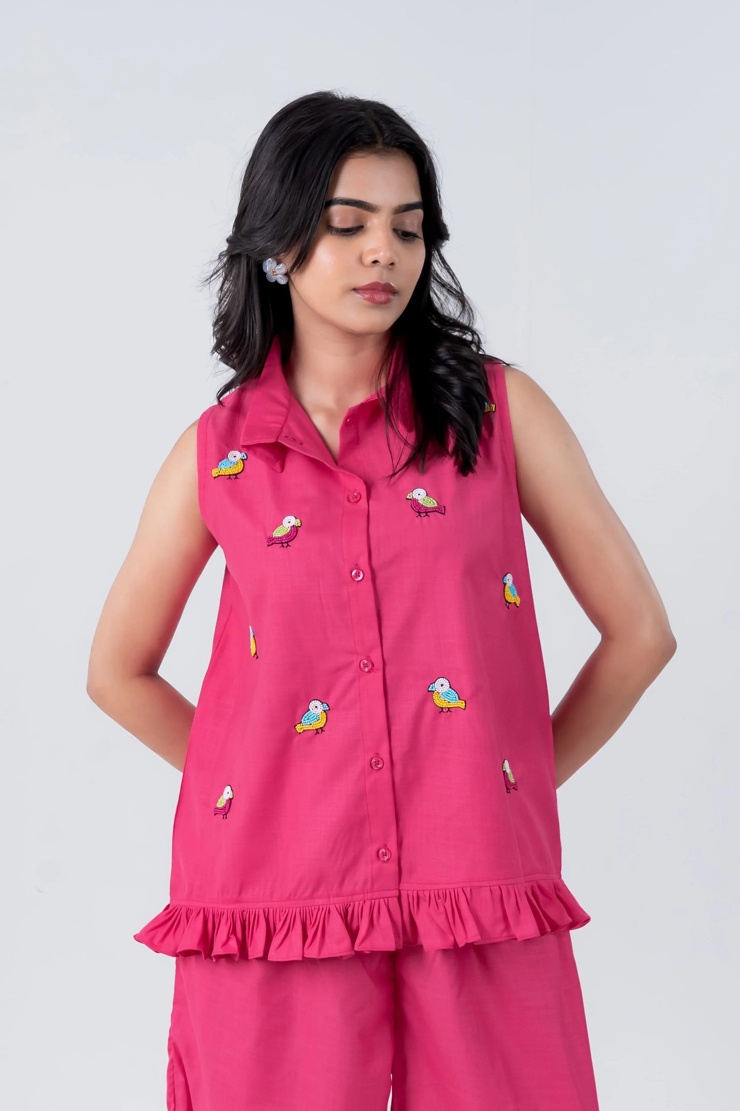 Pink sleeveless shirt with colorful bird embroidery and ruffle hem, paired with matching pants for women's casual wear