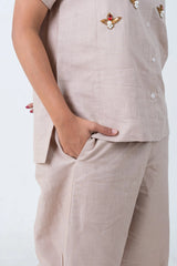 Beige women's co-ord set with pearl and red gem embellishments, button front, and side pockets