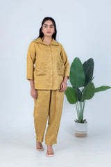 Mustard yellow linen co-ord set with sequin pockets, styled with sandals and green plant backdrop