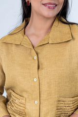 Mustard yellow button-up shirt with embroidered pockets and white buttons, styled with red earrings