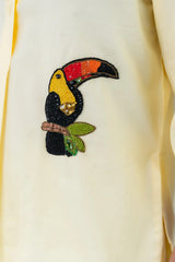Beaded toucan embroidery on cream dress with colorful details