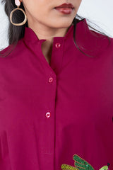 Magenta button-up shirt with floral embroidery and pink buttons