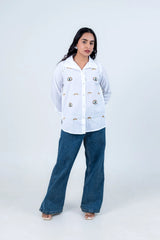 Woman in white embroidered shirt with eye motifs and wide-leg jeans, stylish casual outfit