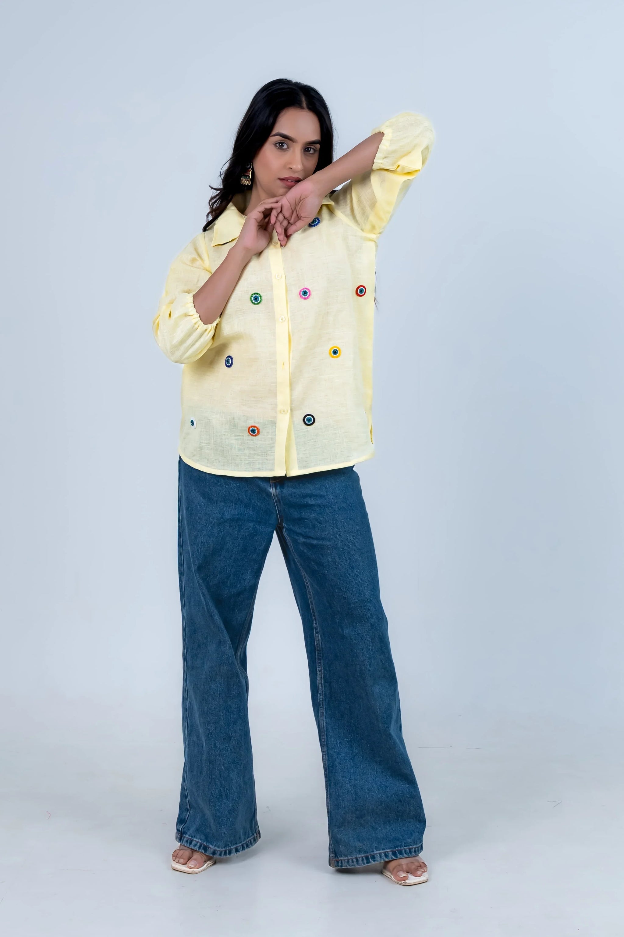 Yellow button-up shirt with colorful embroidery paired with wide-leg jeans