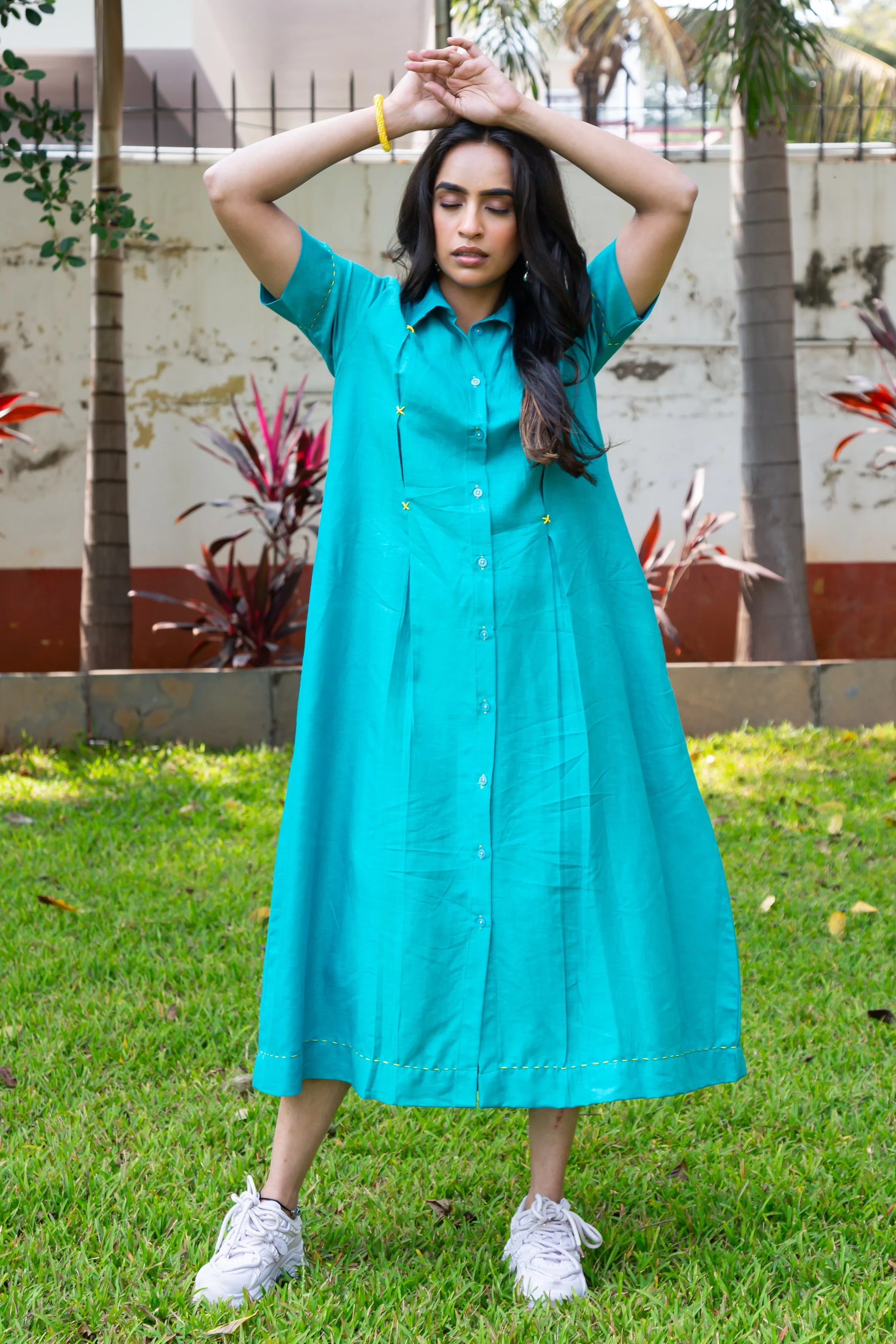 Turquoise button-down dress with yellow stitching, paired with white sneakers, worn outdoors on grass.