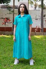 Teal button-down dress with yellow stitching, paired with white sneakers, styled outdoors on grass.