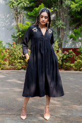 Black embroidered midi dress with floral details, paired with beige heels for a stylish look