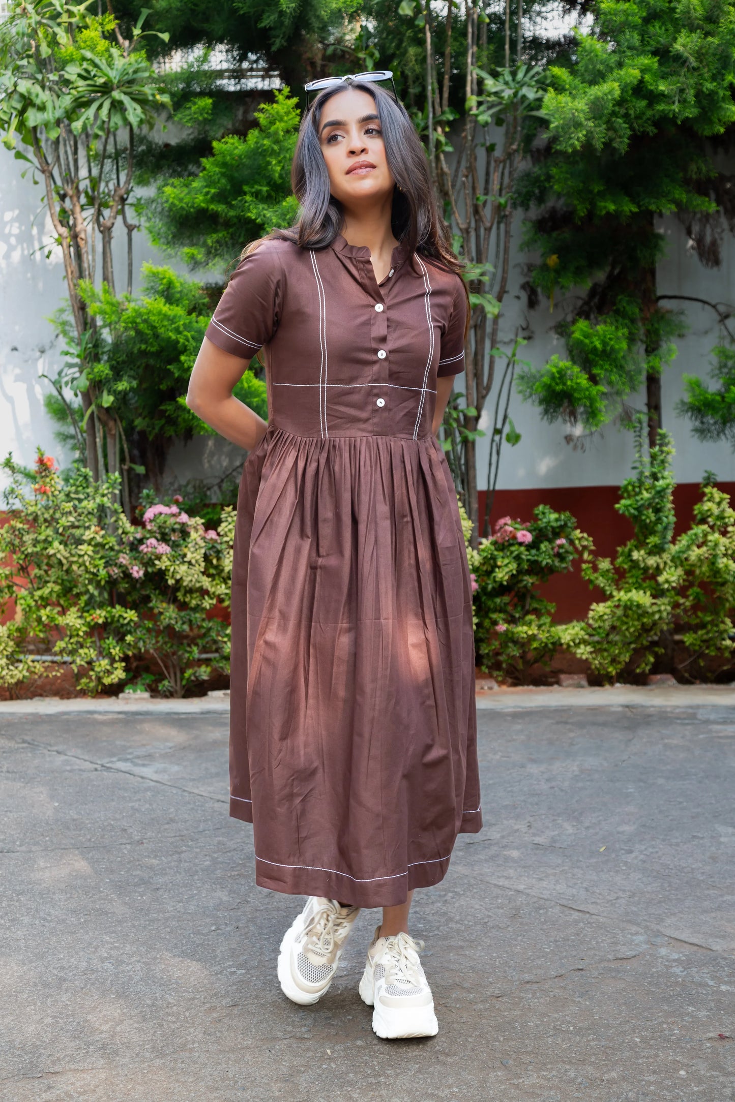 Brown midi dress with white stitching, paired with white sneakers, styled for everyday comfort