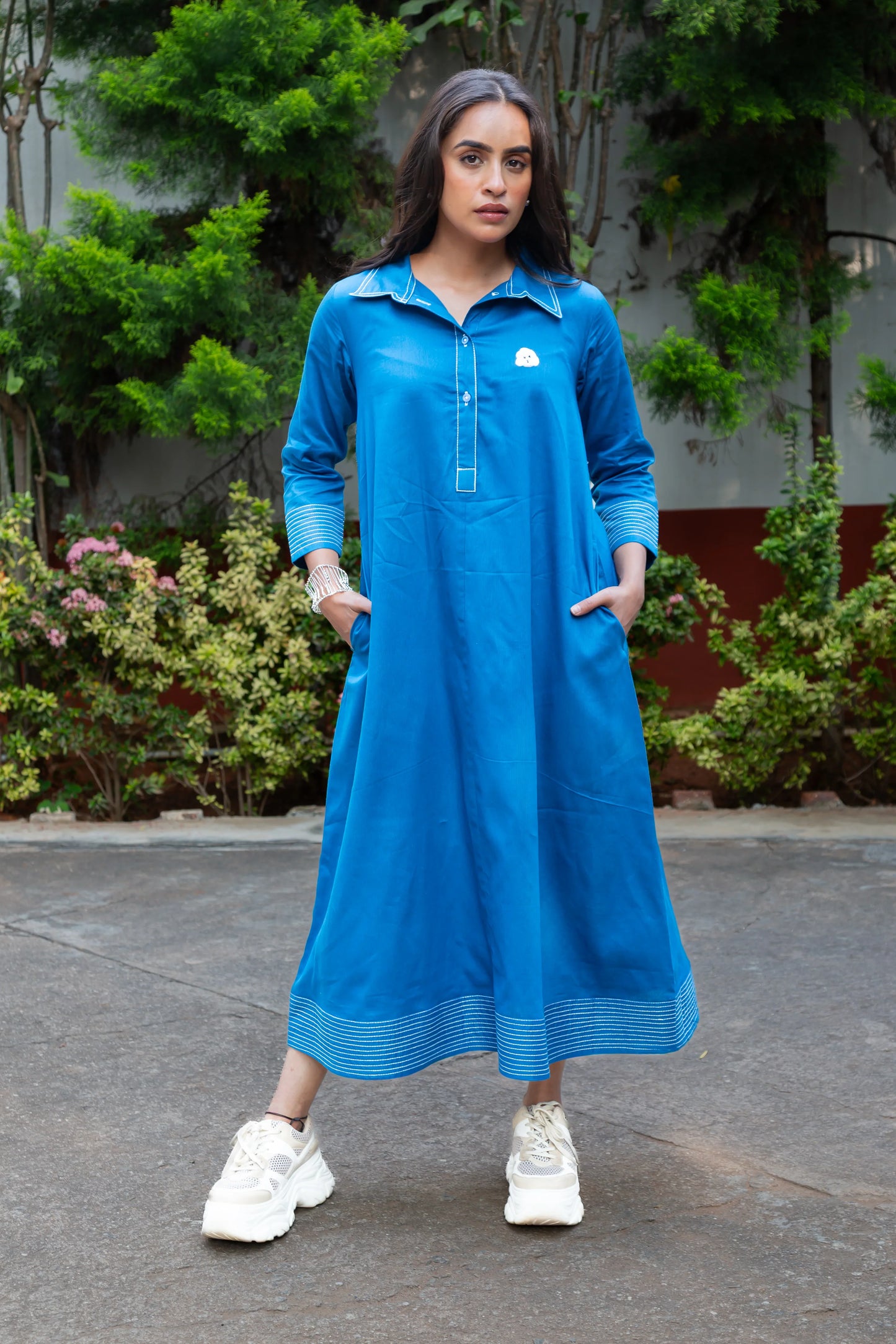 Blue long-sleeve dress with white trim and pocket, paired with white sneakers, ideal for casual outings.