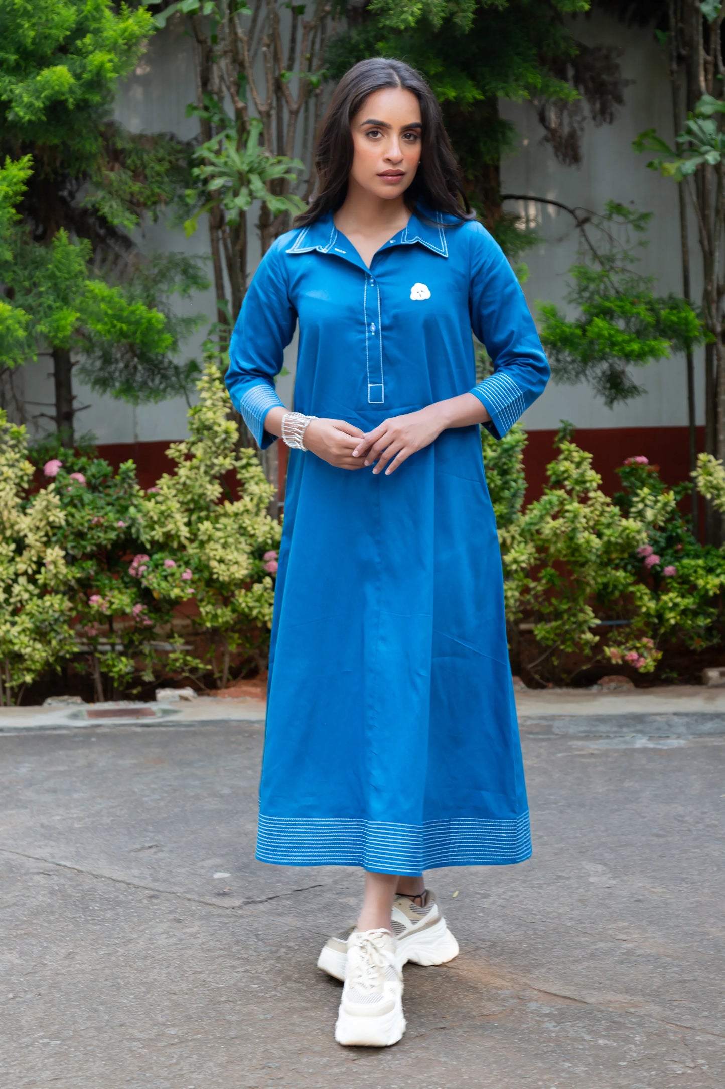 Blue long-sleeve dress with white trim and embroidery, paired with white sneakers, ideal for casual outings.