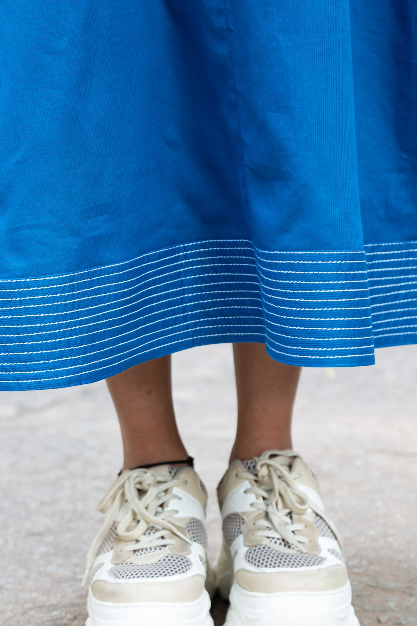 Blue dress with white striped hem paired with beige mesh sneakers