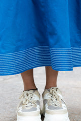 Blue dress with white striped hem paired with beige mesh sneakers