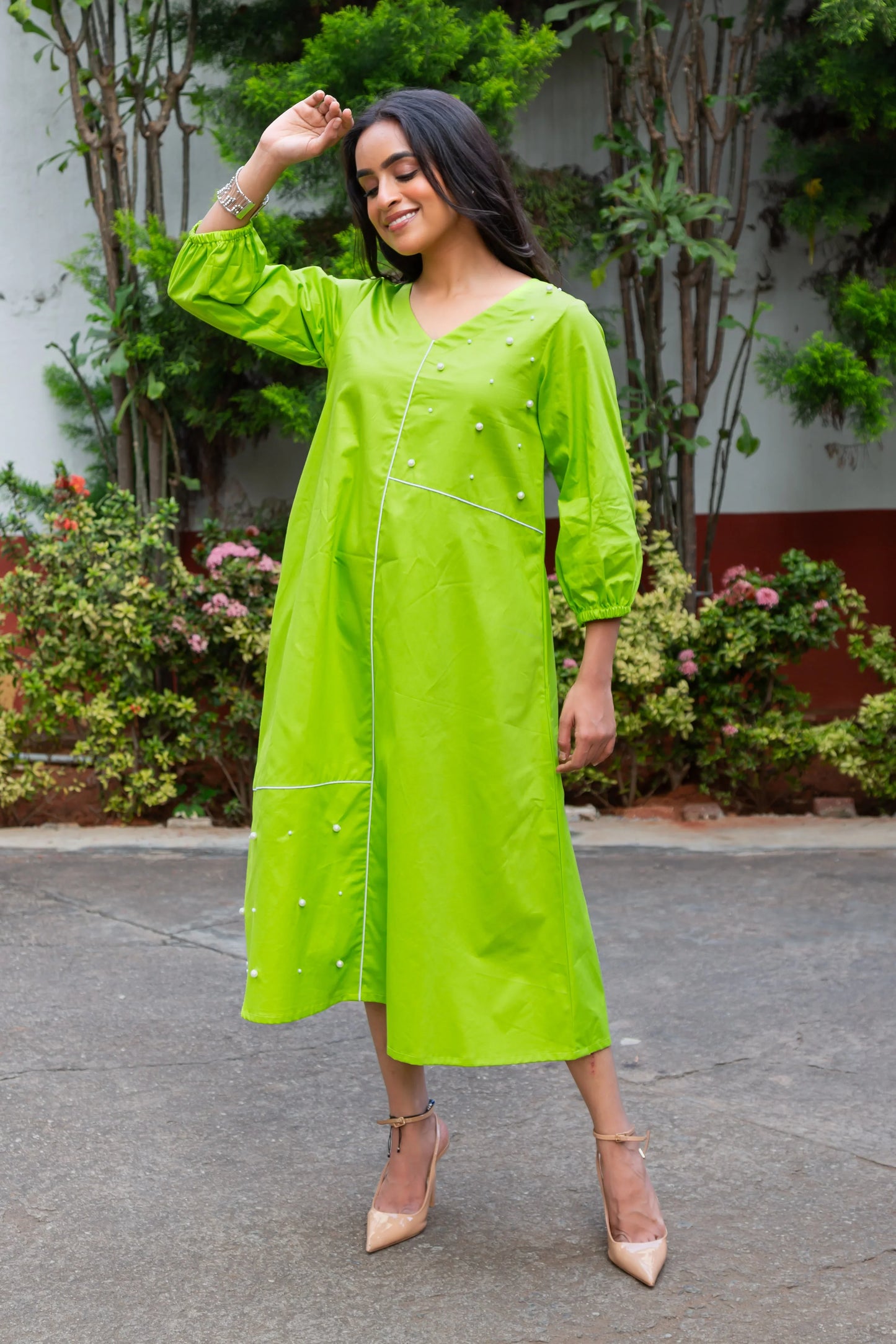 Vibrant green midi dress with pearl details and puff sleeves, styled with beige heels for a chic look.