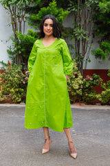 Vibrant green midi dress with pearl embellishments and white piping, paired with beige heels