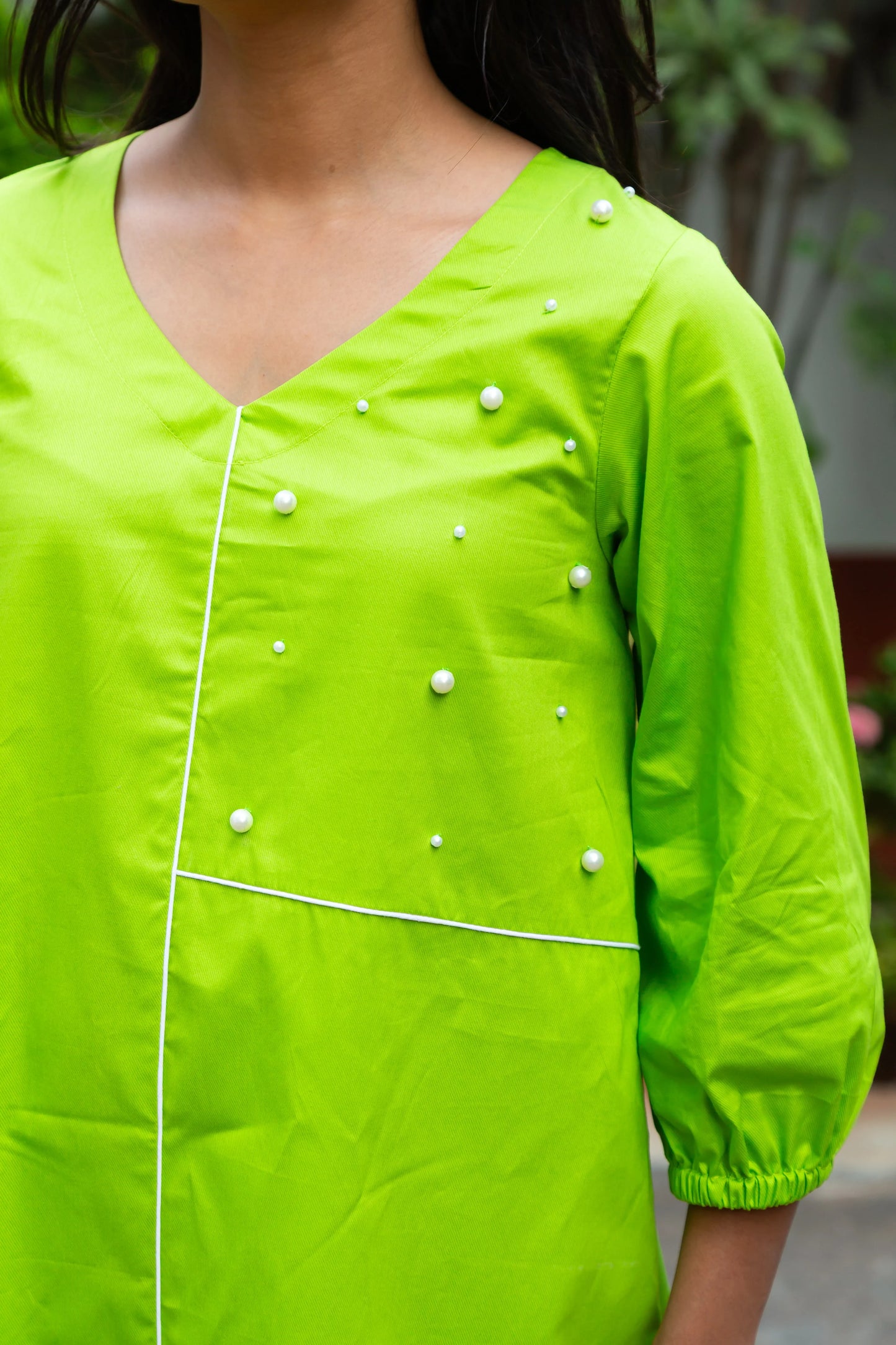 V-neck lime green dress with pearl embellishments and white piping details