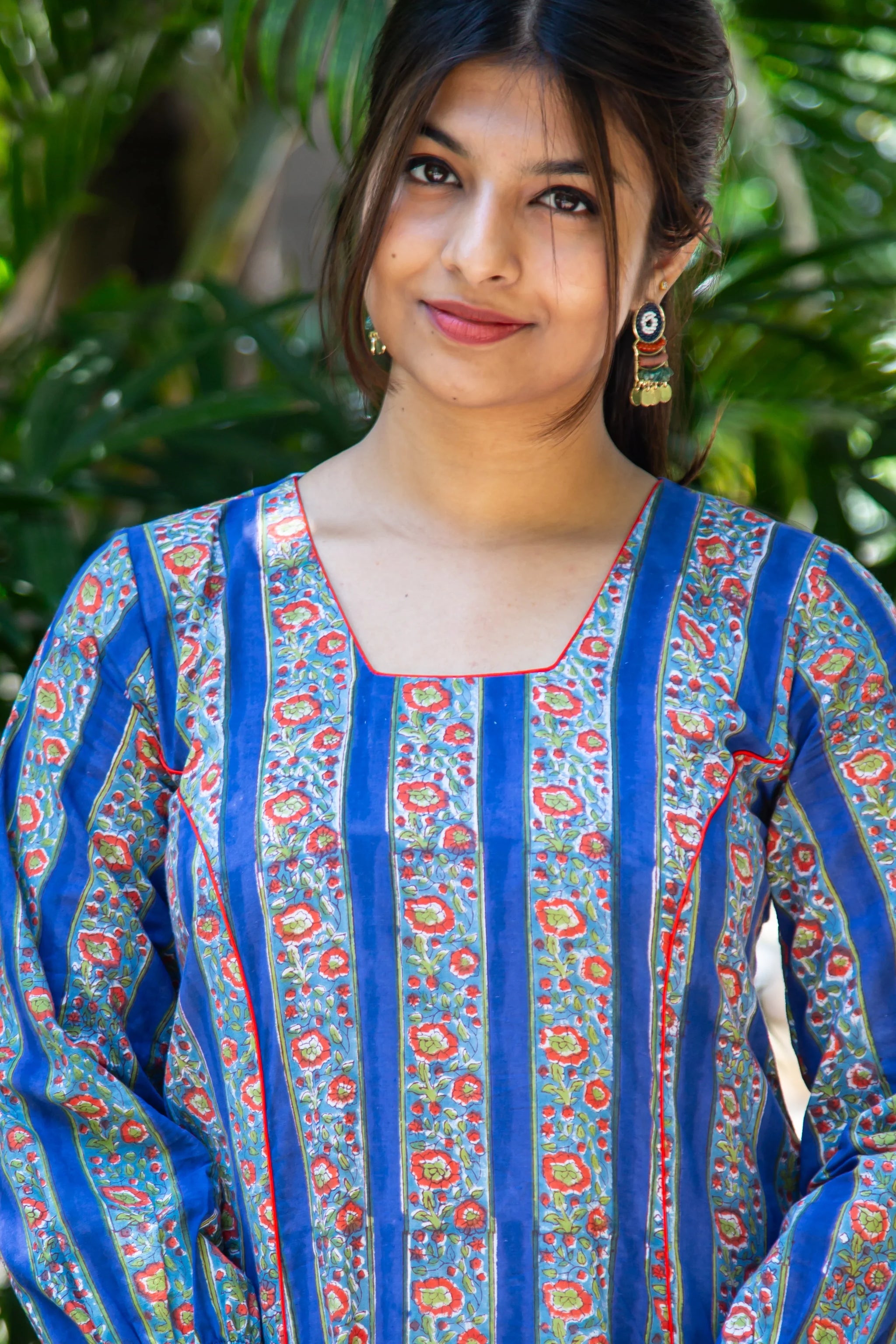 Woman in blue floral printed kurta with red trim, styled with statement earrings, perfect for everyday wear.