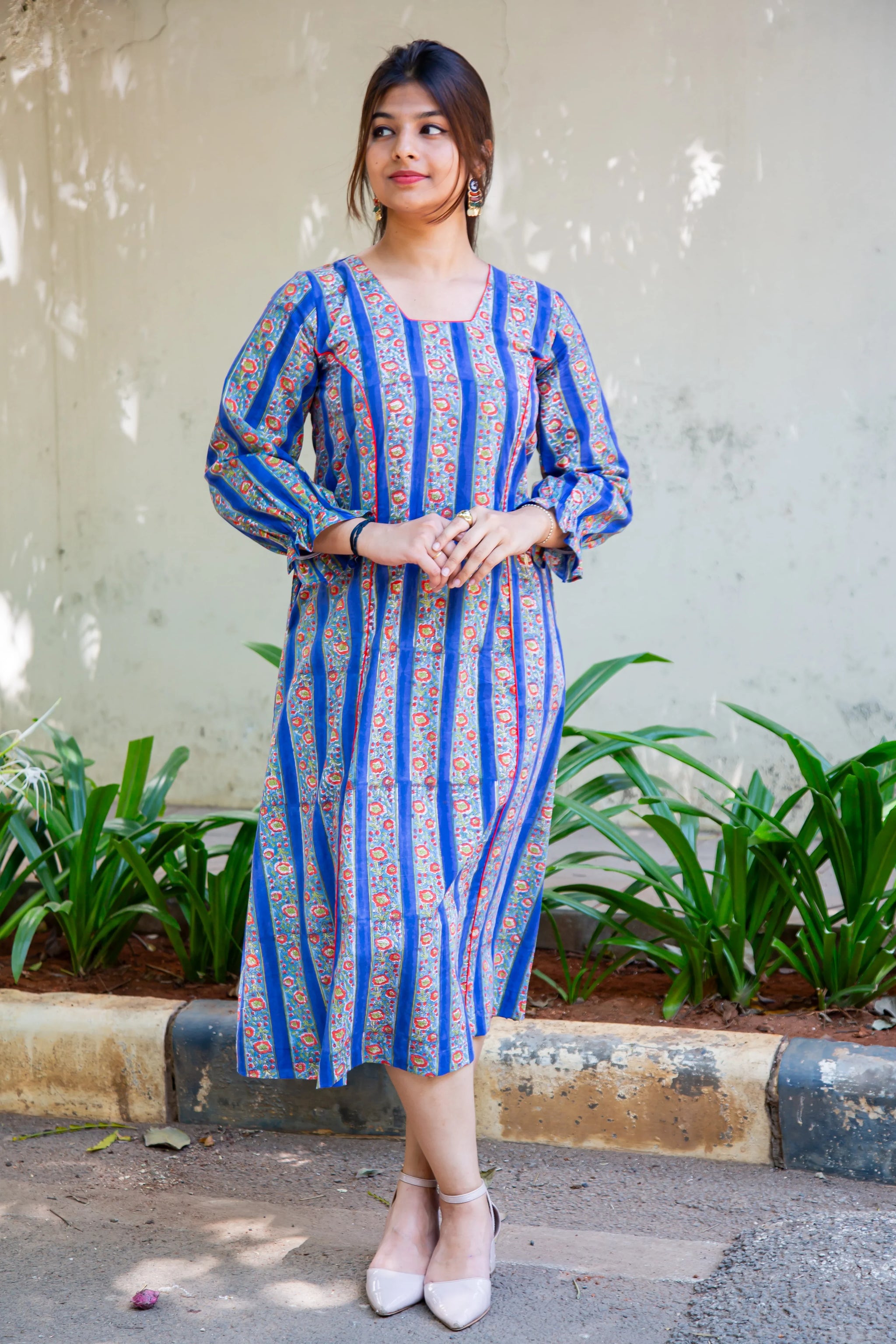 Blue striped floral dress with long sleeves, paired with beige heels, perfect for everyday wear.