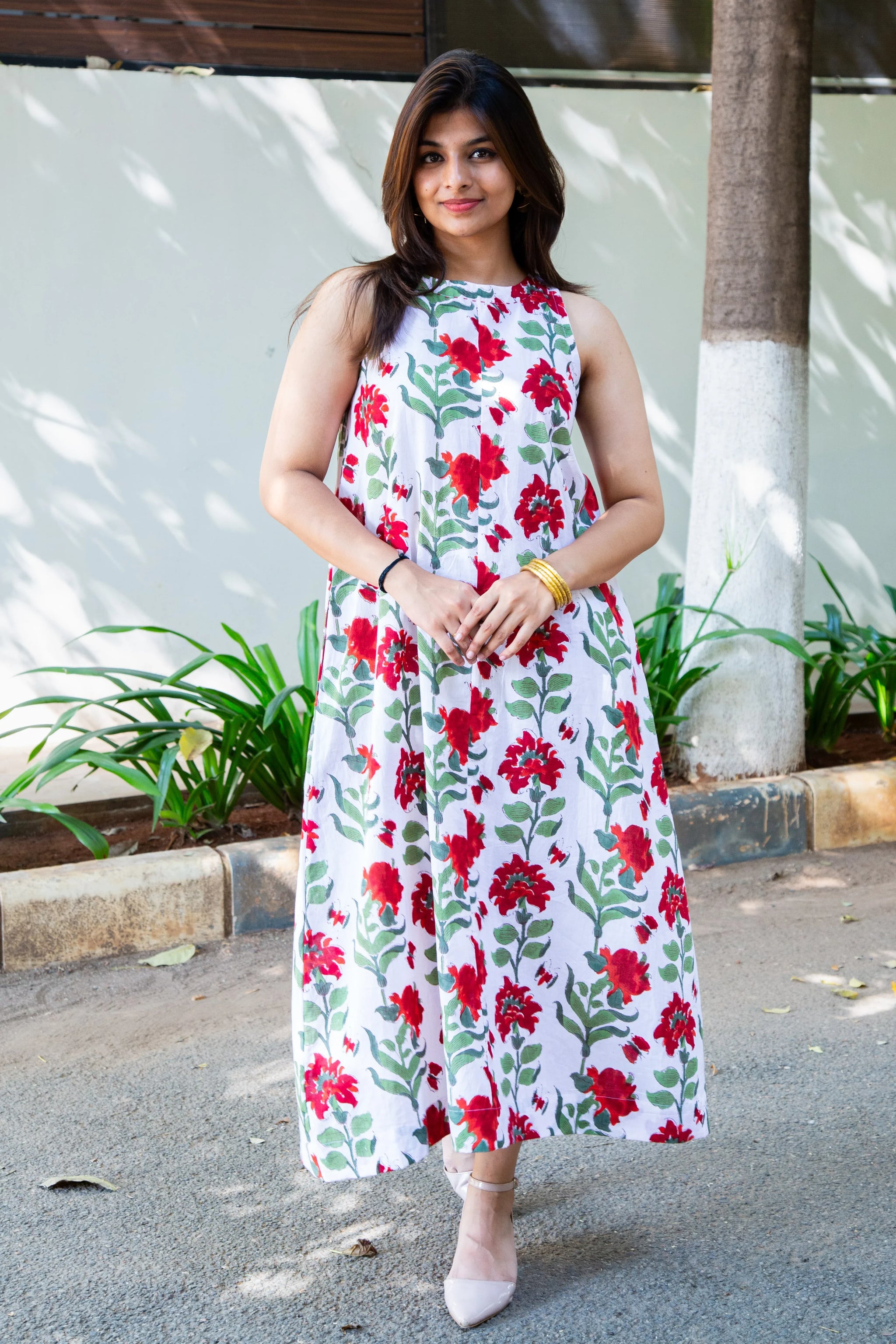White floral midi dress with red blooms and green leaves, styled for casual elegance