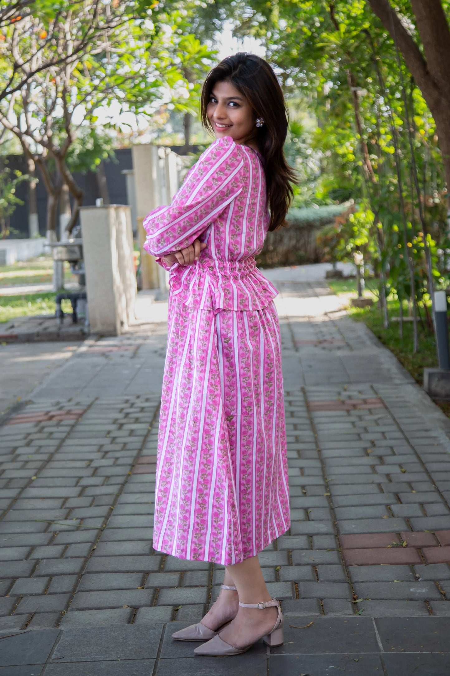 Pink striped floral dress with ruffled waist, styled for everyday comfort and elegance.