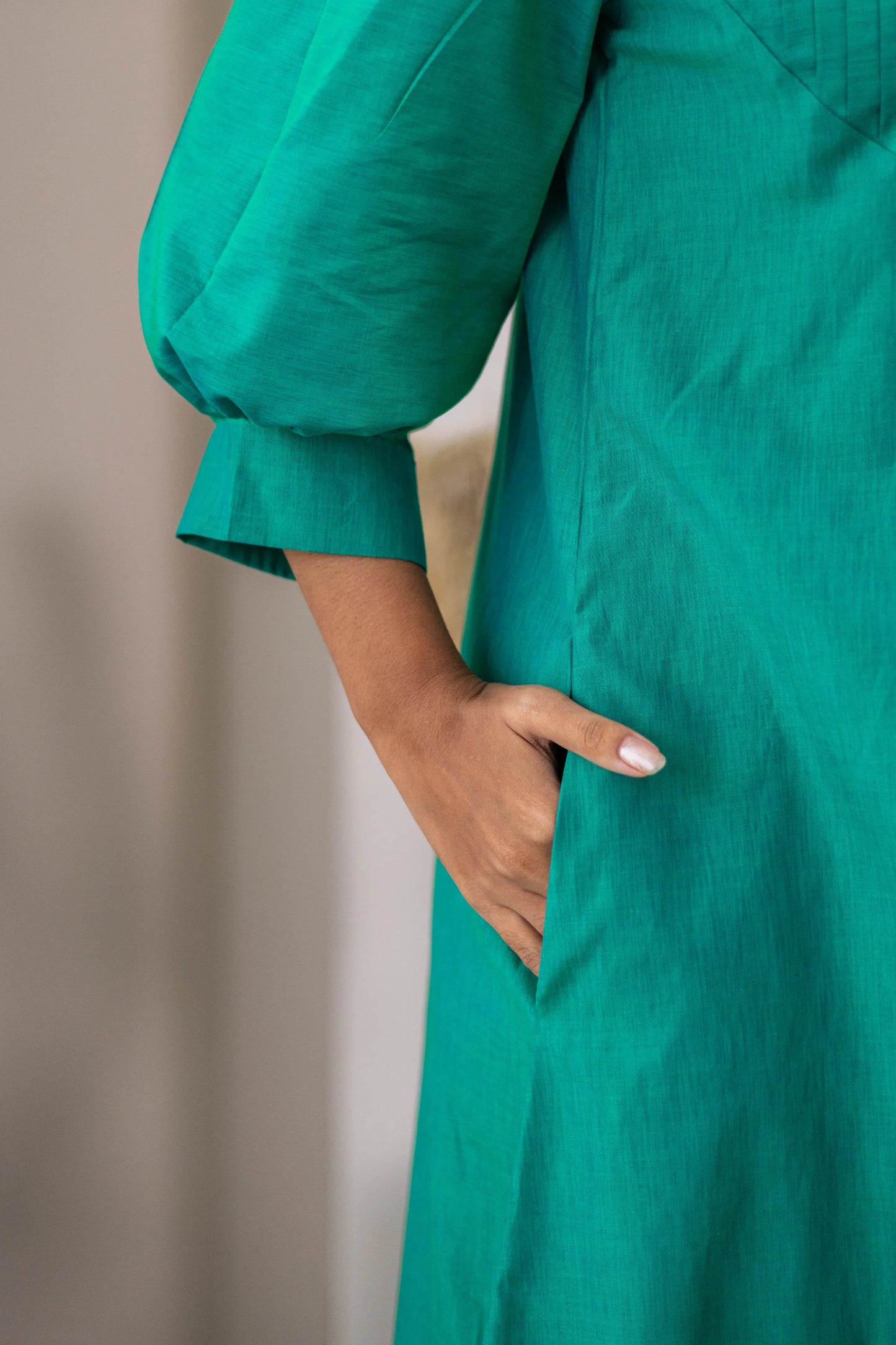 Close-up of woman wearing green dress with puff sleeve and hand in pocket