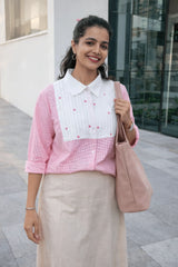 Woman in pink and white floral blouse with beige skirt, carrying pink tote bag, stylish everyday outfit