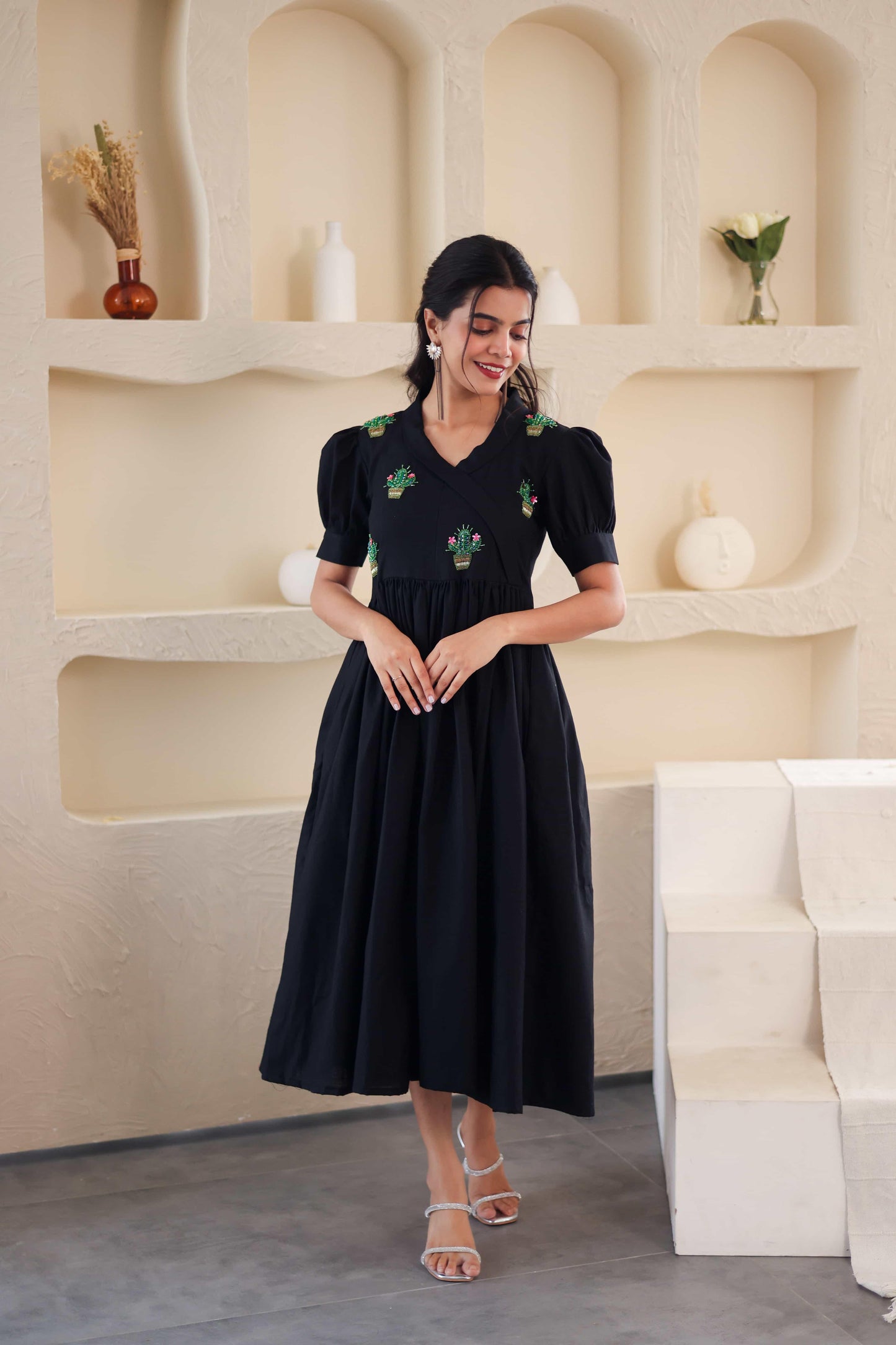 Woman wearing a black cotton midi dress with green cactus embroidery and puff sleeves