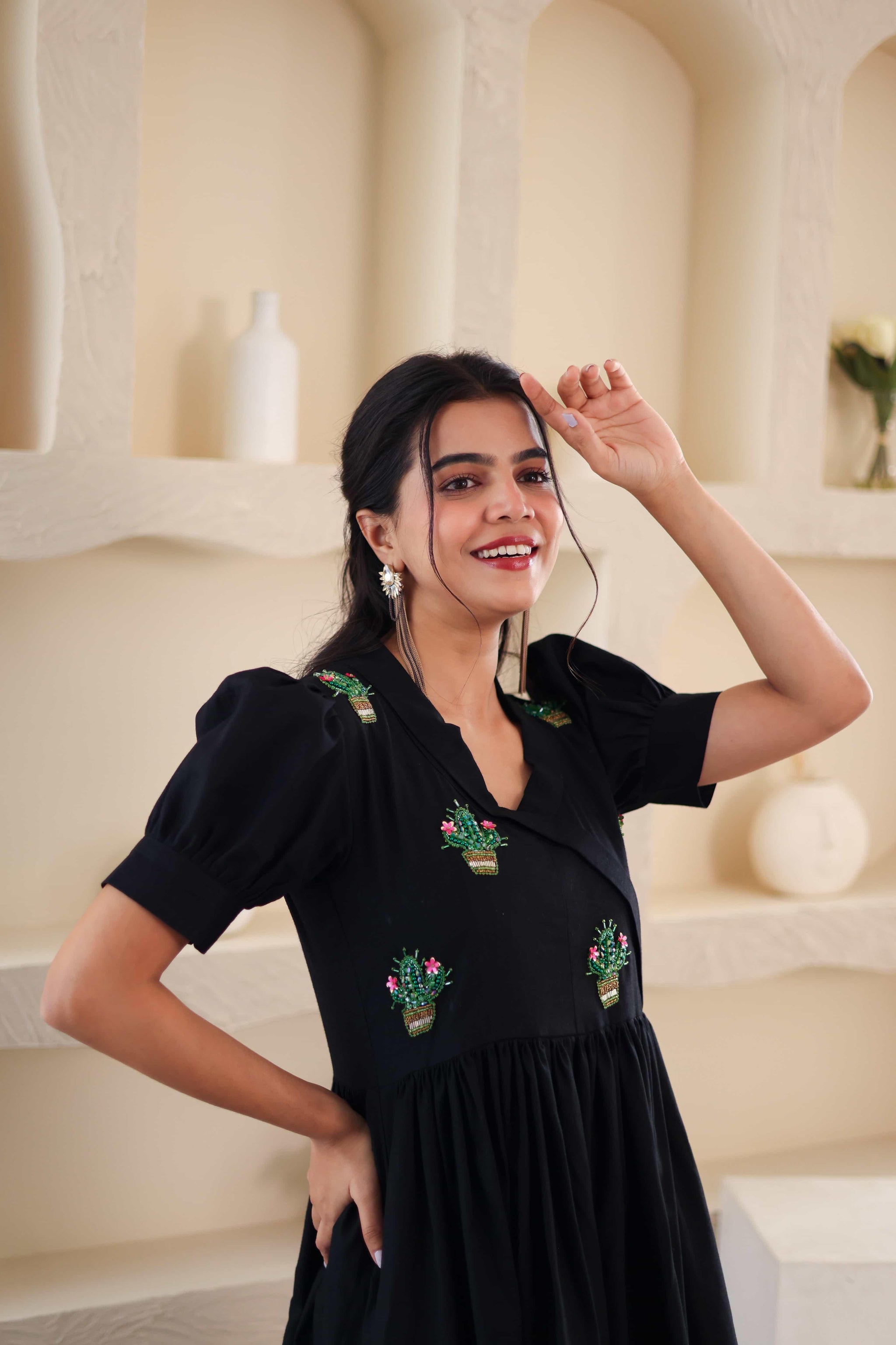 Woman wearing a black cotton dress with cactus embroidery, puff sleeves, and v-neck