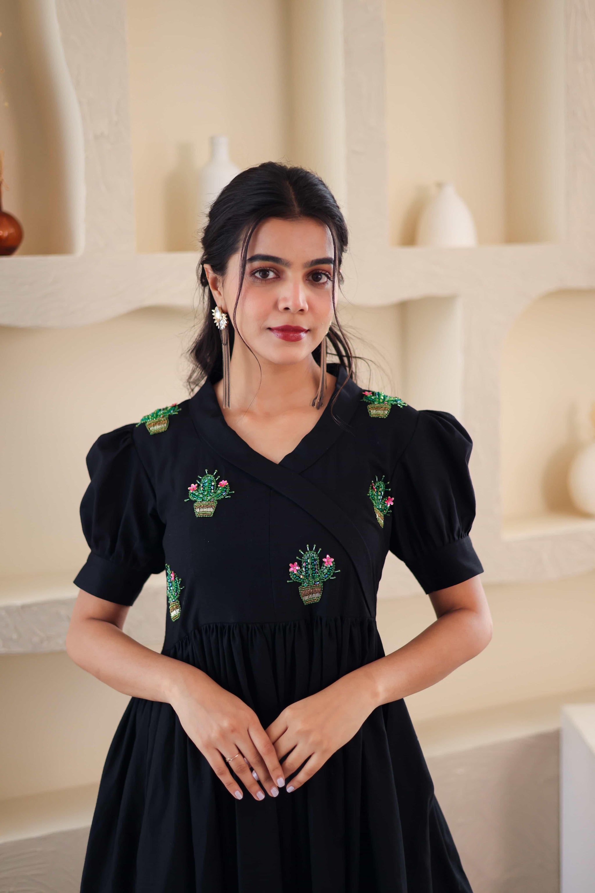 Woman in black cotton dress with green cactus embroidery and puff sleeves