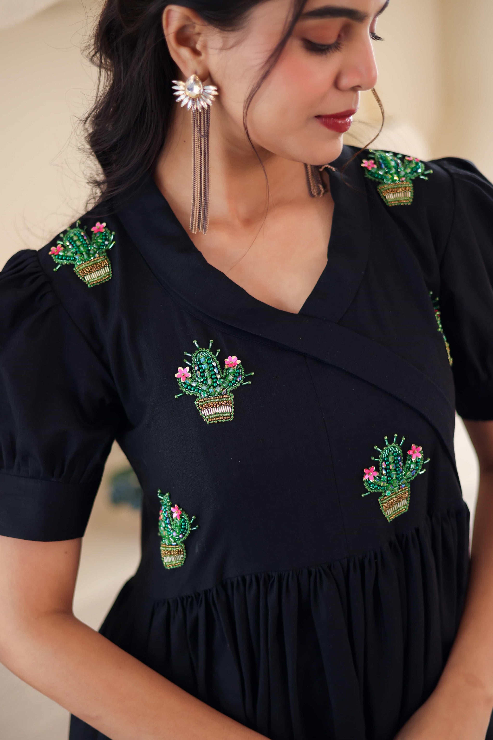 Black cotton dress with cactus embroidery and puff sleeves, close-up view