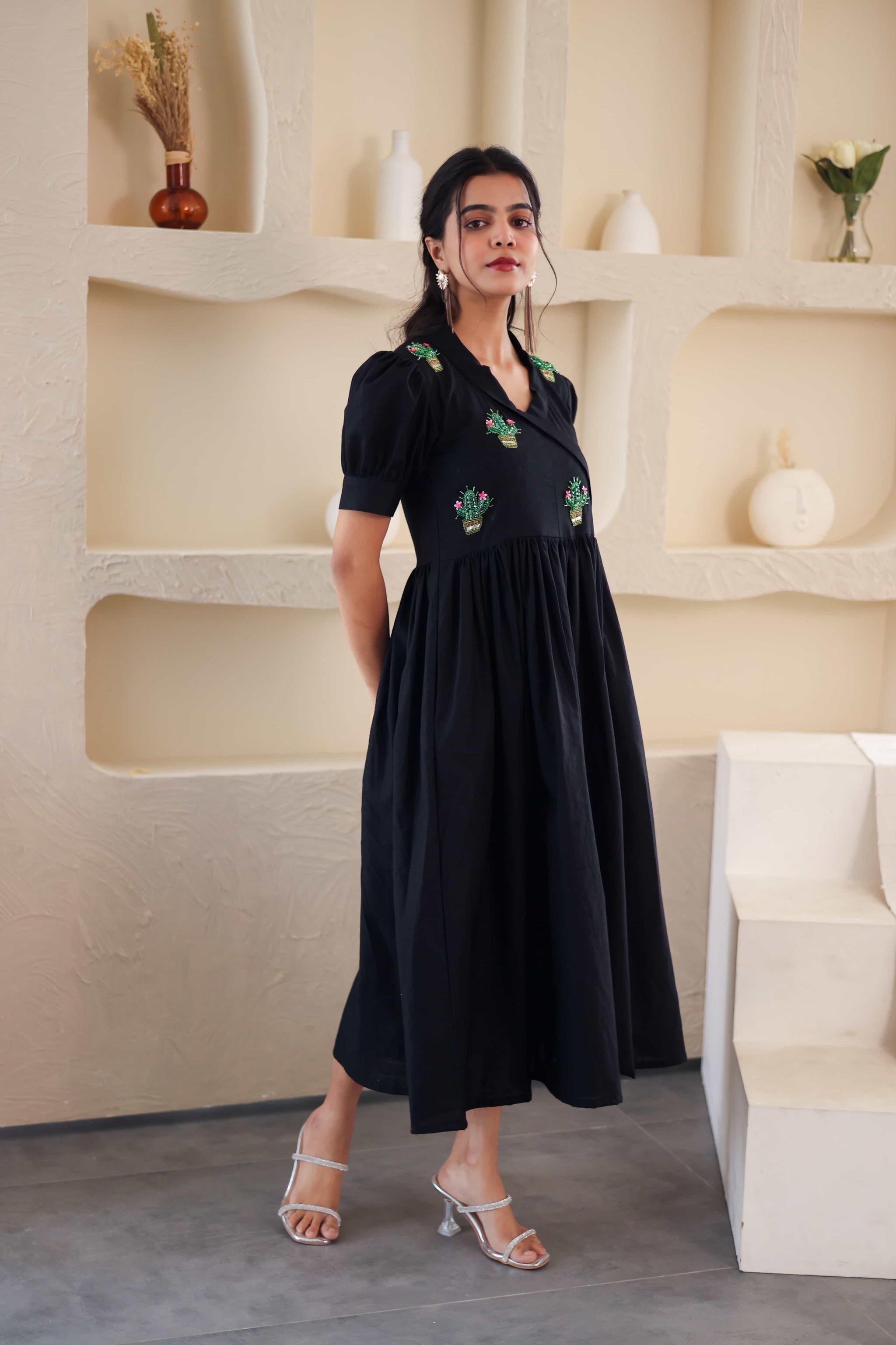 Woman wearing black cotton midi dress with green embroidered cacti, puff sleeves