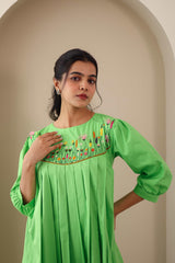 Woman wearing green embroidered cotton poplin dress with floral pleats detail